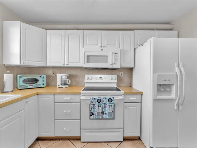 a kitchen with granite countertop white cabinets and refrigerator