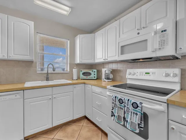 a kitchen with granite countertop white cabinets and white appliances