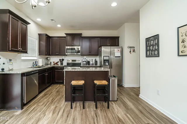 a kitchen with stainless steel appliances granite countertop a refrigerator a stove microwave and cabinets with wooden floor