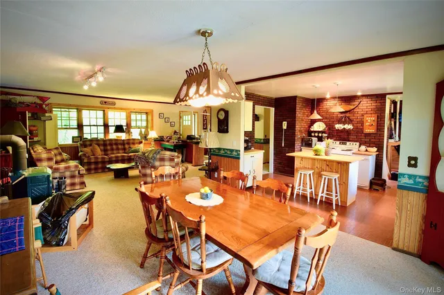 a view of a dining room and livingroom with furniture wooden floor a chandelier