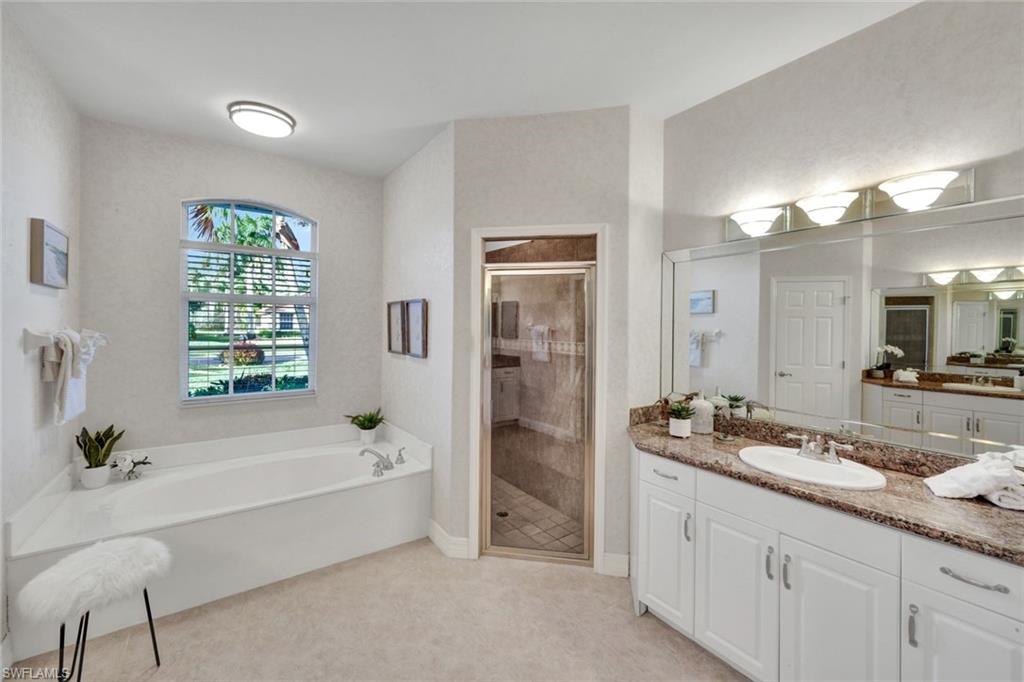 7830 Twin Eagle Lane Fort Myers, FL 33912 - Photo 19 of 31 a spacious bathroom with a granite countertop tub sink a mirror a shower and vanity