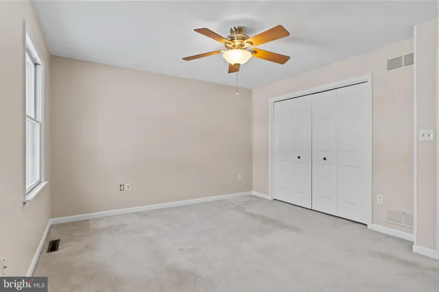 an empty room with a window and ceiling fan