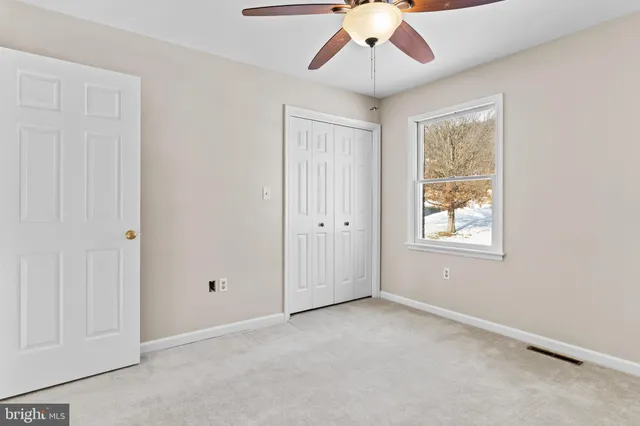 an empty room with windows and fan