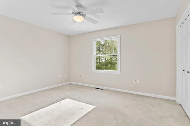 an empty room with a window and a fan
