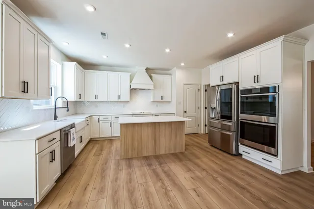 a large kitchen with stainless steel appliances and white cabinets