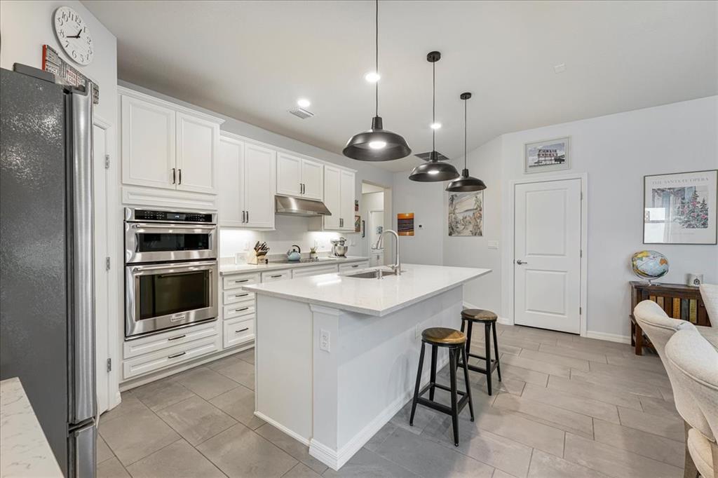 8258 Northwest 79th Avenue Tamarac, FL 33321 - Photo 12 of 38 a kitchen with kitchen island granite countertop a stove a sink a oven a dining table and chairs with wooden floor