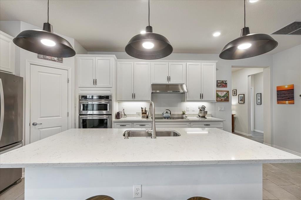 8258 Northwest 79th Avenue Tamarac, FL 33321 - Photo 16 of 38 a kitchen with stainless steel appliances a white table chairs and a refrigerator