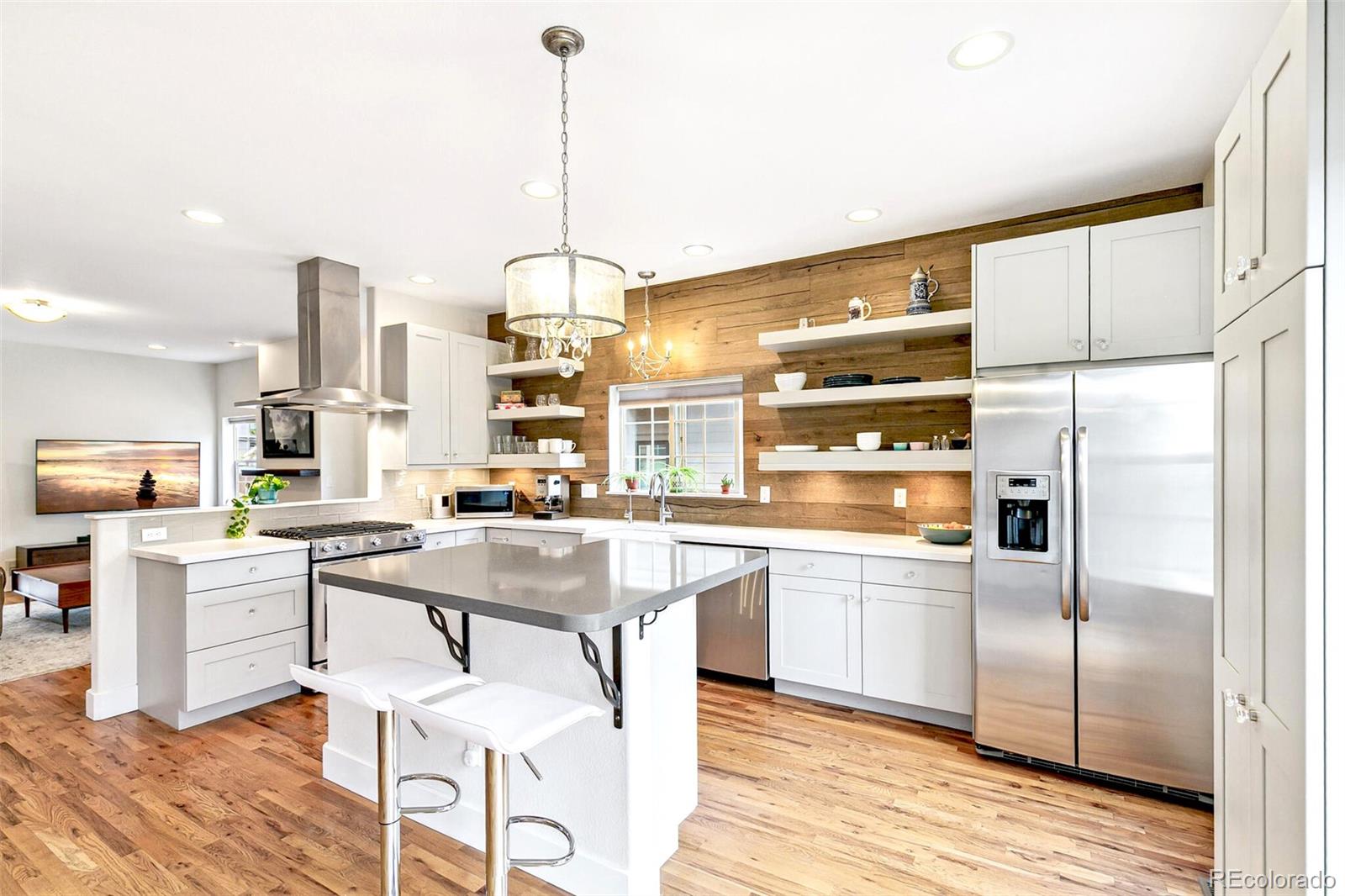 4530 Quitman Street Denver, CO 80212 - Photo 17 of 50 a kitchen with stainless steel appliances kitchen island granite countertop a refrigerator a oven a stove and a dining table with wooden floor