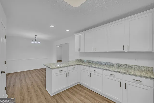 a kitchen with a sink dishwasher and white cabinets with wooden floor
