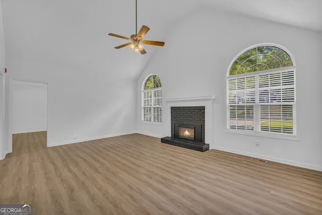 a view of empty room with wooden floor fireplace and a window