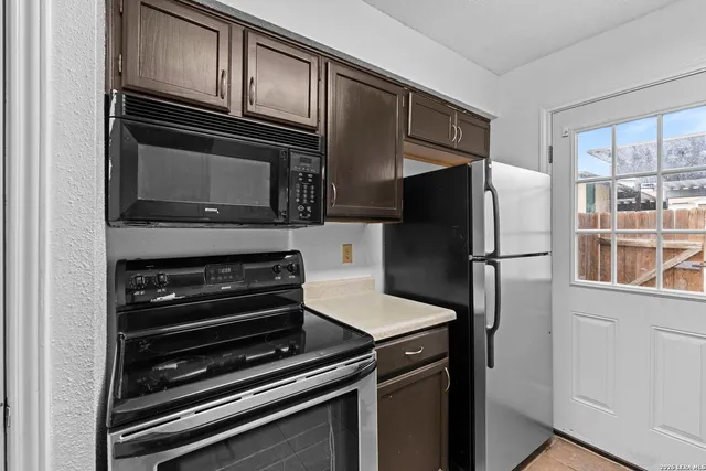 a kitchen with granite countertop a refrigerator stove and microwave