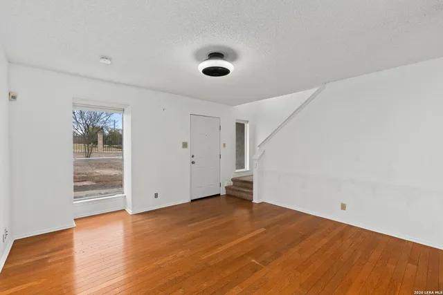 an empty room with wooden floor and windows