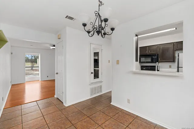 a view of a hallway with an empty room and a kitchen
