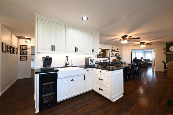 a kitchen with stainless steel appliances kitchen island granite countertop a stove top oven a sink a dining table and chairs with wooden floor