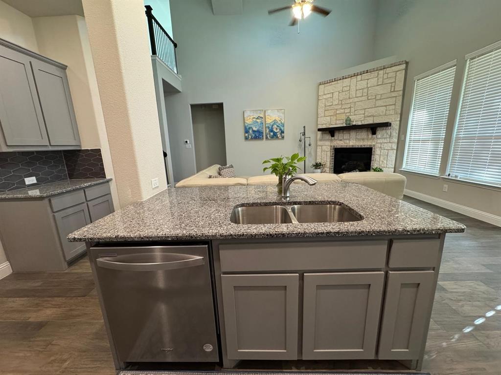 1204 Sundrop Drive Little Elm, TX 75068 - Photo 6 of 24 a kitchen with granite countertop a sink stainless steel appliances white cabinets and a fireplace