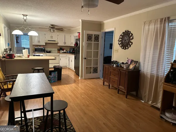a kitchen with stainless steel appliances granite countertop a refrigerator a stove top oven and a dining table with wooden floor