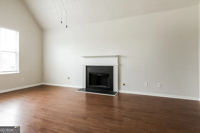 an empty room with wooden floor and a fireplace