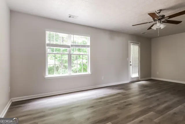 an empty room with wooden floor and windows