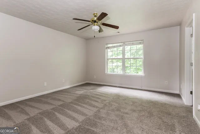 an empty room with ceiling fan and windows