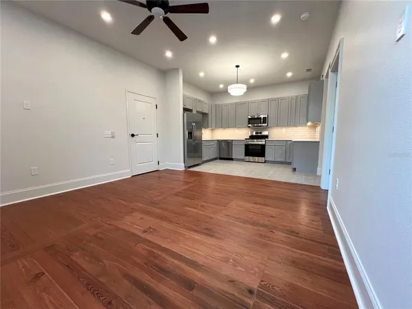 a kitchen with stainless steel appliances granite countertop a refrigerator a stove top oven a sink and dishwasher with wooden floor