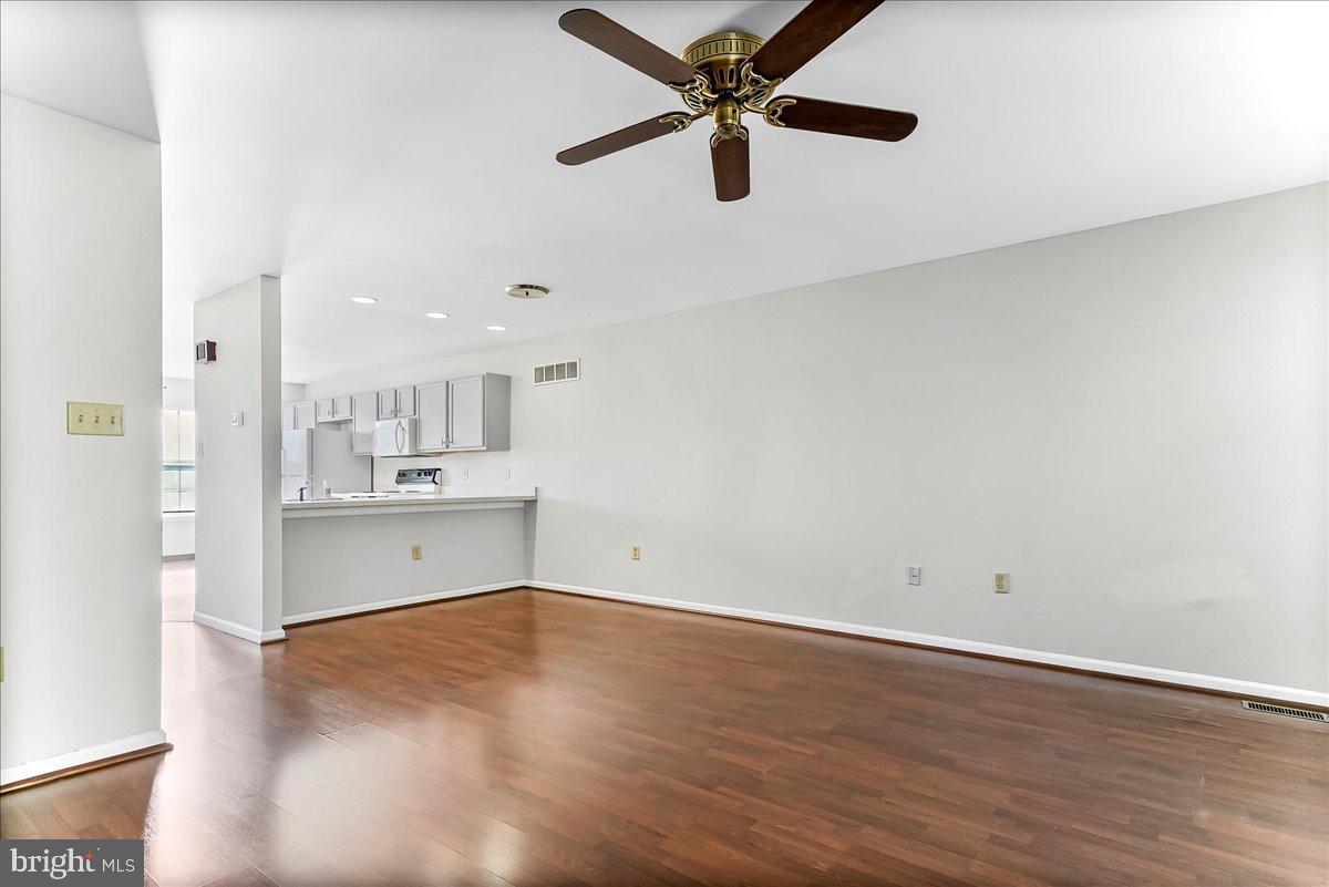 103 Bonnybrook Road Middletown, DE 19709 - Photo 5 of 32 an empty room with wooden floor a ceiling fan and kitchen view