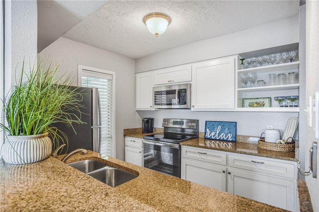14300 Aloha Street, Unit 231 Corpus Christi, TX 78418 - Photo 9 of 37 a kitchen with granite countertop a sink and a stove