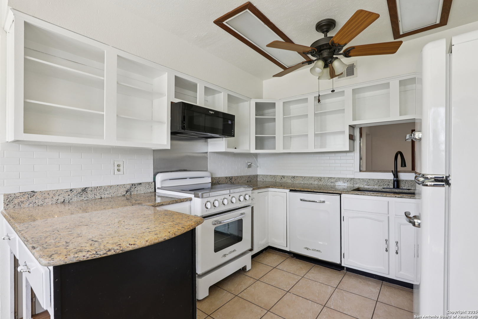 4380 Bear Springs Road Pipe Creek, TX 78063 - Photo 12 of 60 a kitchen with granite countertop a sink stainless steel appliances and white cabinets