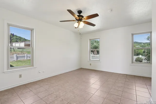 a view of empty room with wooden floor and ceiling fan