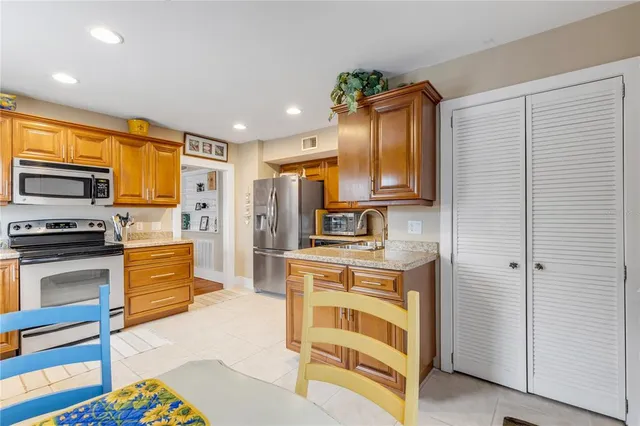 a kitchen with stainless steel appliances granite countertop a sink dishwasher and a refrigerator with wooden floor