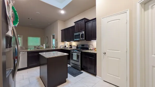 a kitchen with stainless steel appliances granite countertop a refrigerator a sink a stove a microwave and a refrigerator