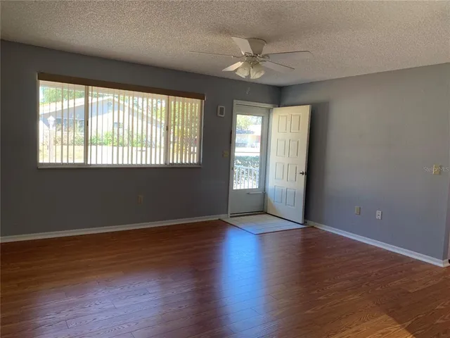 a view of an empty room with wooden floor and a window