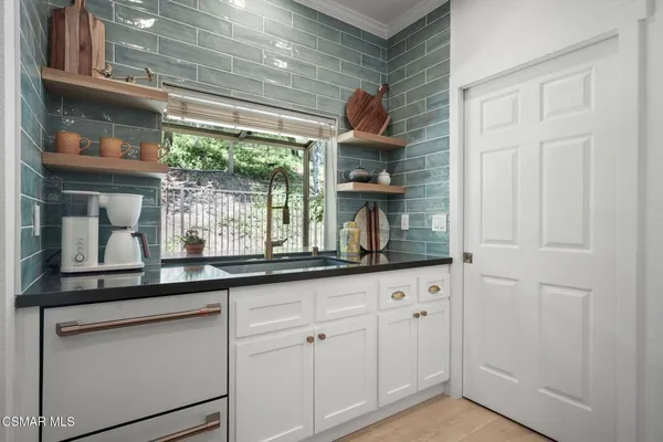 a kitchen with white cabinets and a window