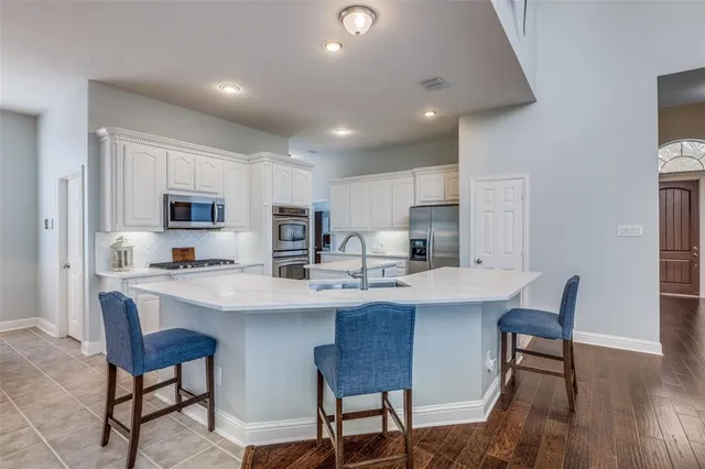 a large white kitchen with a stove a sink dishwasher and a fireplace with wooden floor