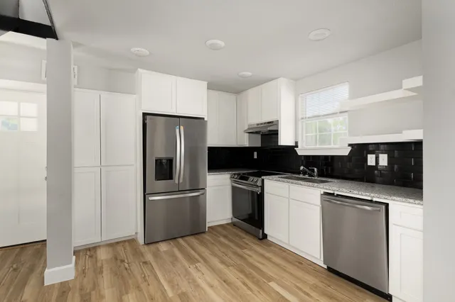 a kitchen with stainless steel appliances granite countertop a refrigerator a stove top oven a sink and dishwasher