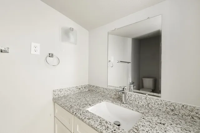 a bathroom with a granite countertop sink and a mirror