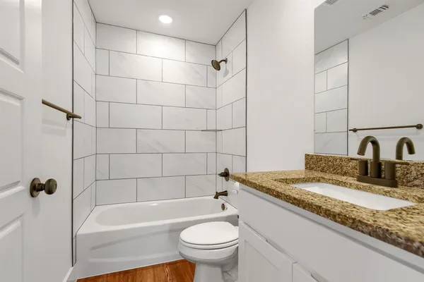 a bathroom with a granite countertop sink a toilet and bathtub