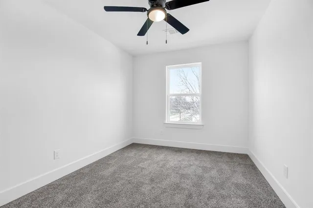 an empty room with a window and a fan