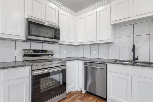 a kitchen with granite countertop white cabinets and appliances