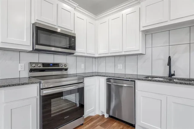 a kitchen with granite countertop white cabinets and appliances