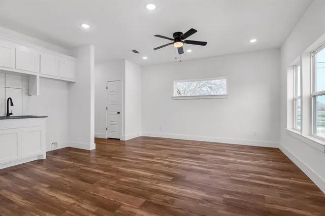 a view of an empty room with a window and wooden floor