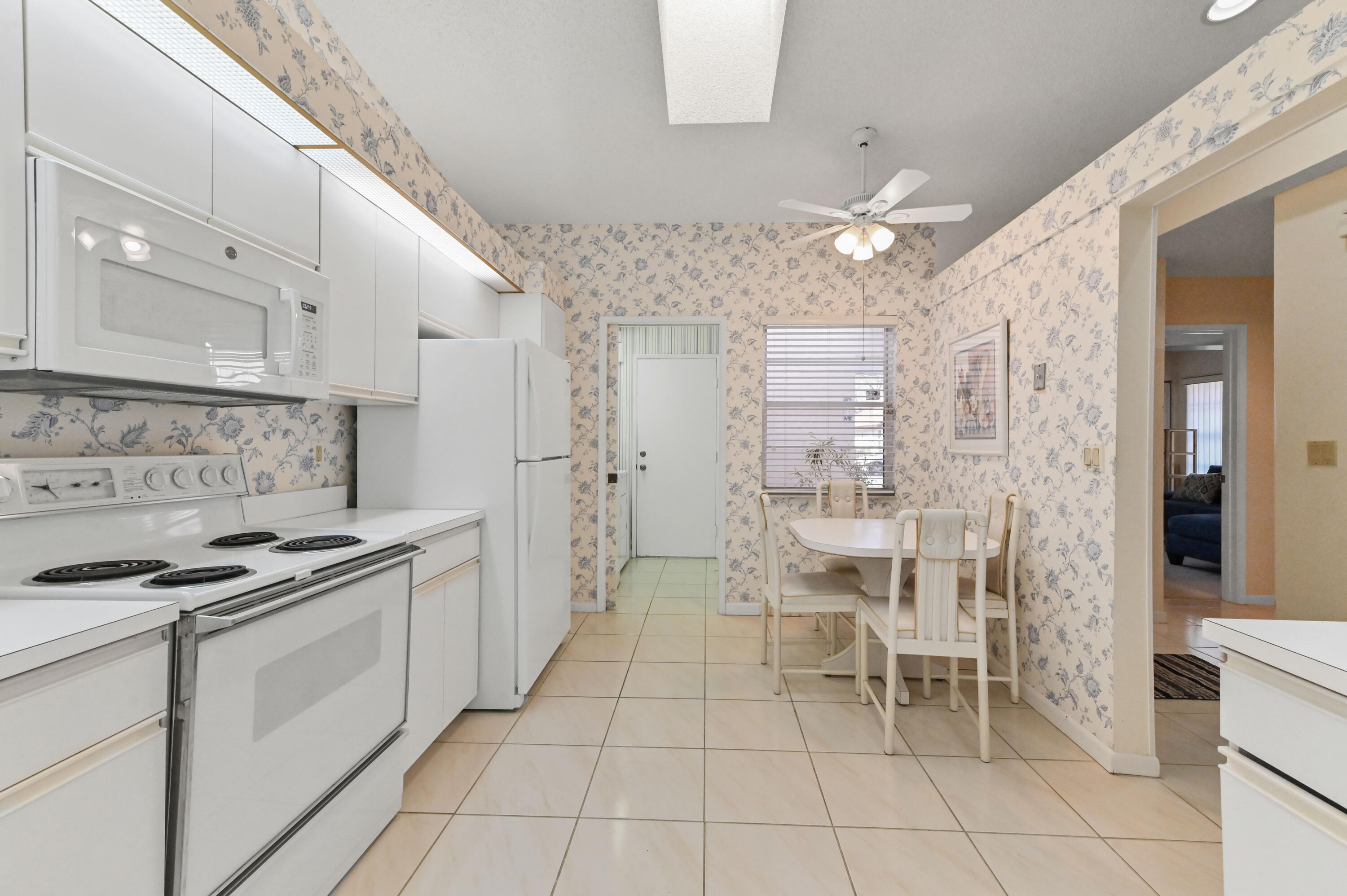 6040 Waldwick Circle Delray Beach, FL 33484 - Photo 9 of 75 a kitchen with stainless steel appliances a table chairs and a refrigerator