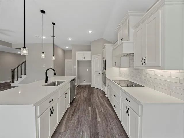 a kitchen with white cabinets appliances and a sink