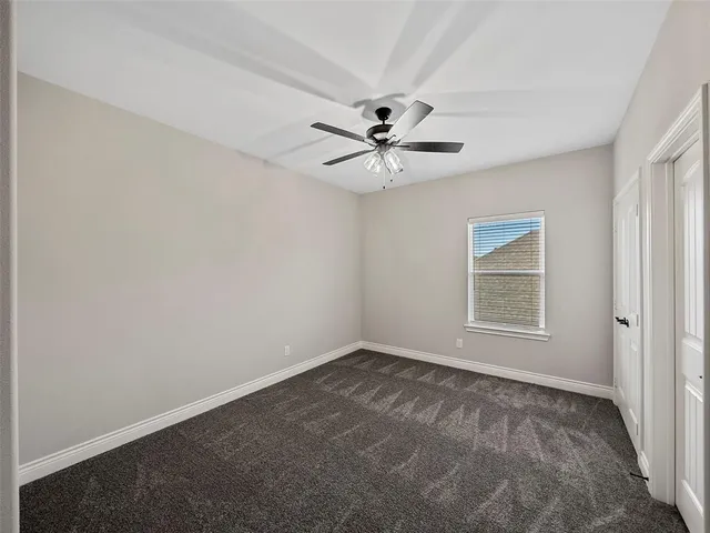 an empty room with a chandelier fan and windows