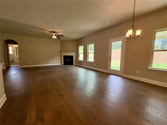 an empty room with wooden floor fireplace and windows