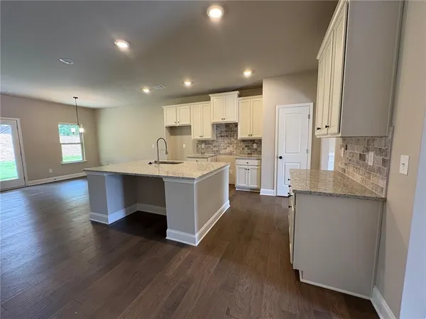 a large kitchen with stainless steel appliances a large counter top a sink a refrigerator and a stove