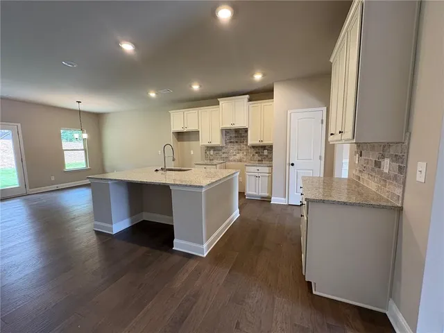 a large kitchen with stainless steel appliances a large counter top a sink a refrigerator and a stove