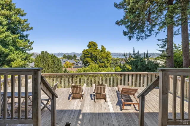a balcony with wooden floor outdoor seating and trees in the background