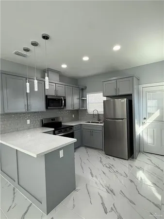 a kitchen with a refrigerator a stove top oven a sink and cabinets