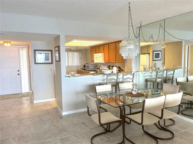 a dining room with furniture a chandelier and kitchen view