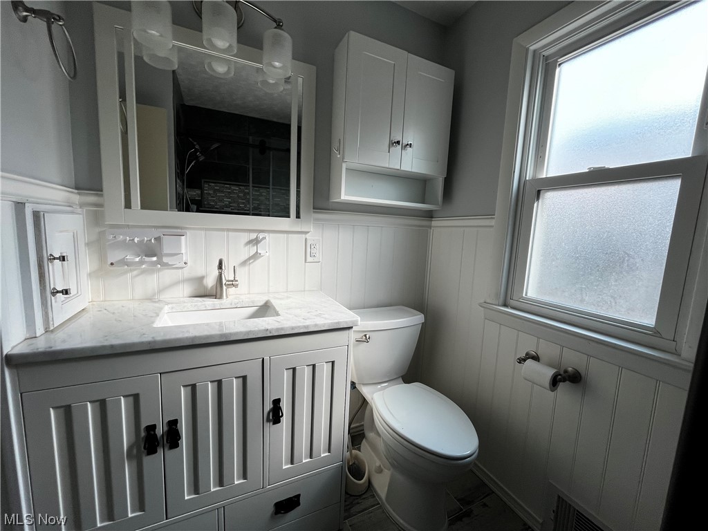 30824 Clarmont Road Willowick, OH 44095 - Photo 17 of 24 Bathroom with backsplash, a healthy amount of sunlight, toilet, and oversized vanity